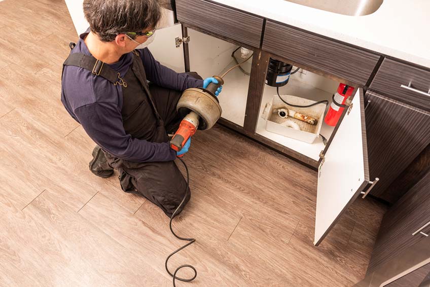 plumber unclogging a kitchen sink drain