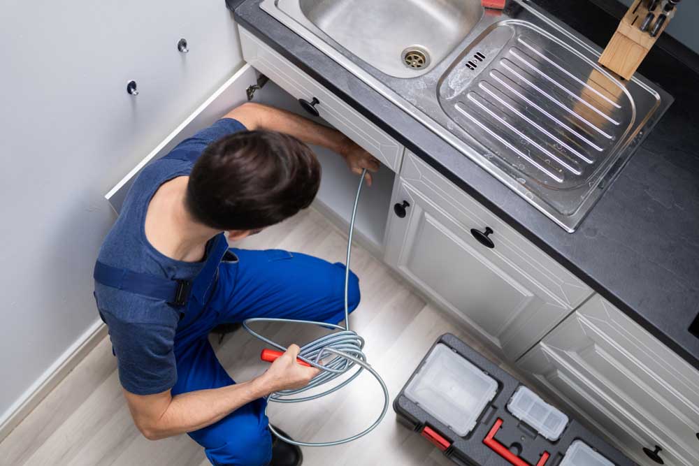 Male Plumber Cleaning Clogged Sink Pipe Richmond, KY.